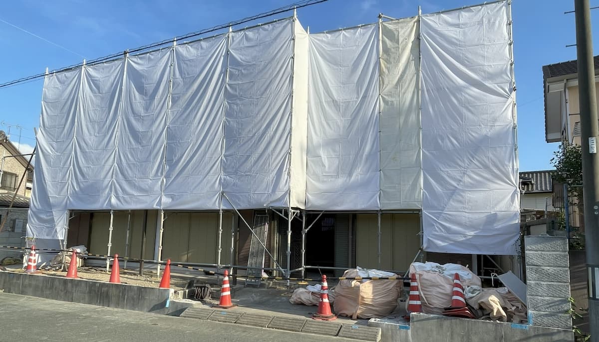 解体工事の現場で建物全体を養生シートで覆い近隣に配慮する伊藤設備総業